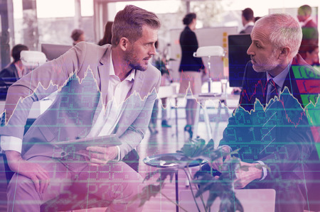 Stocks and shares against business people interacting while using digital tabletの写真素材