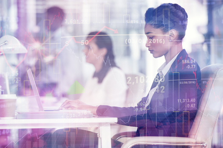 Stocks and shares against focused businesswoman working on laptop