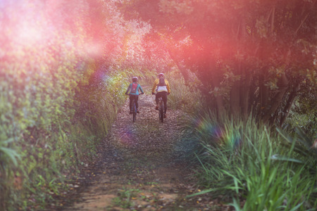 Rear view of biker couple cycling in countryside forestの写真素材