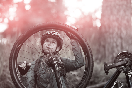 Female biker repairing mountain bike in countrysideの写真素材