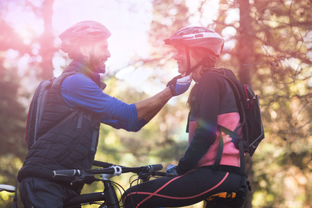 Man adjusting bicycle helmet of woman in countrysideの写真素材