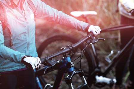 Midsection of female biker with mountain bike in countrysideの写真素材