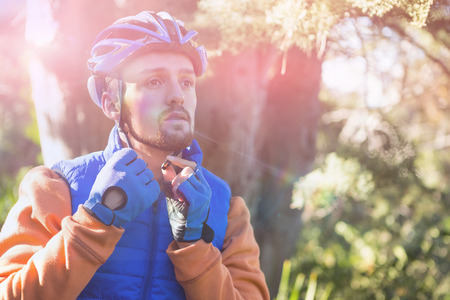 Male mountain biker wearing bicycle helmet in forest on sunny dayの写真素材