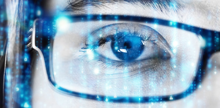 Digitally generated black and blue matrix against eye of a woman wearing spectacles