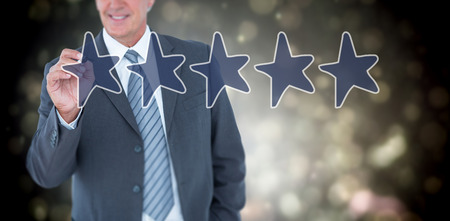 Businessman writing with black marker against black abstract light spot designの写真素材