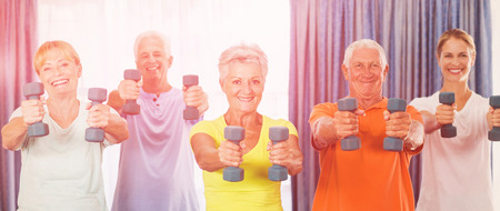 Portrait of seniors exercising with weights during sports classの写真素材