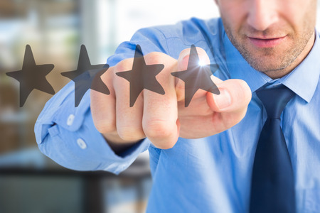 Portrait of confident businessman pointing at you against digital generated image of black starsの写真素材