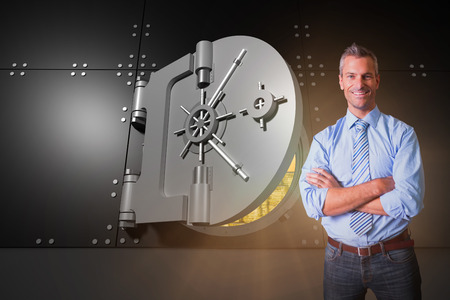 Smiling manager with arms crossed in warehouse against digitally generated half opened safe