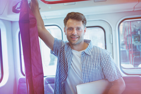 Portrait of handsome man holding laptop while travelling in train