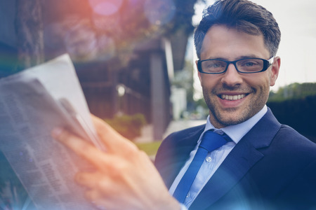 Portrait of handsome businessman reading newspaper outside officeの写真素材