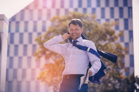 Portrait of businessman holding blazer and newspaperの写真素材