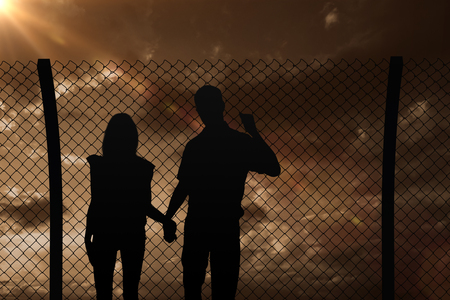 Happy couple walking holding hands against blue and orange sky with cloudsの写真素材