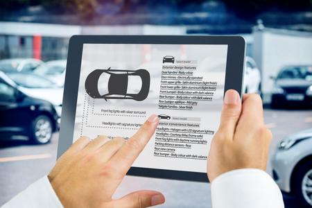 Man using tablet pc against view of row new carの写真素材