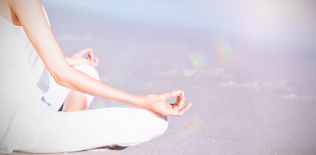 Midsection of woman performing yoga on beachの写真素材