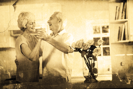 Grey background against cheerful retired couple dancingの写真素材
