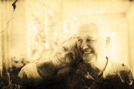 Grey background against happy senior couple smiling at homeの写真素材