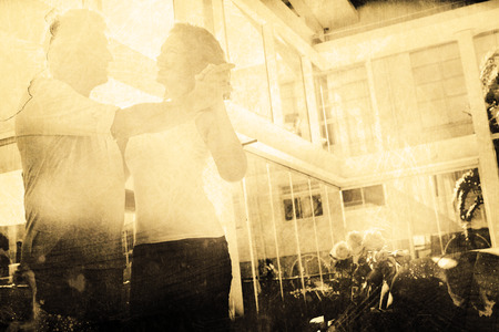 Grey background against smiling mature couple dancingの写真素材