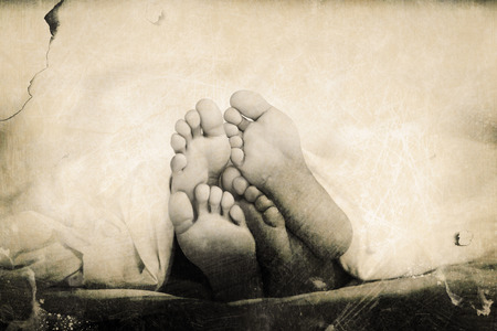 Grey background against feet sticking out from blanketの写真素材