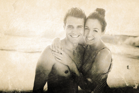 Grey background against portrait of happy couple embracing at beachの写真素材