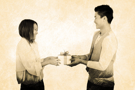 Young man giving present to woman against grey backgroundの写真素材