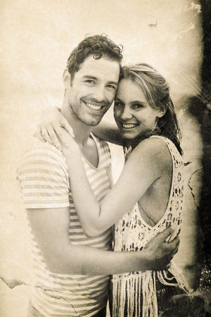 Grey background against portrait of young couple embracing at beachの写真素材