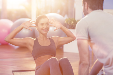 Physiotherapist assisting a female patient while exercising in the clinicの写真素材