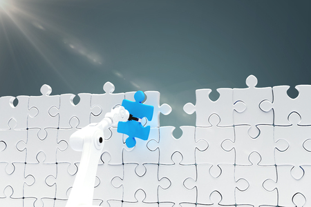 Robotic arm holding blue jigsaw piece by puzzle against blue vignette background 3dの写真素材