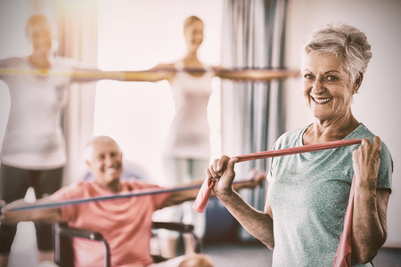 Portrait of seniors exercising with stretching bands during sports classの写真素材