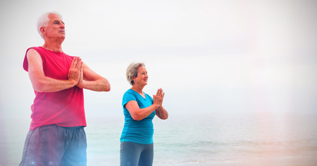 Senior couple in lotus position on the beach on a sunny dayの写真素材