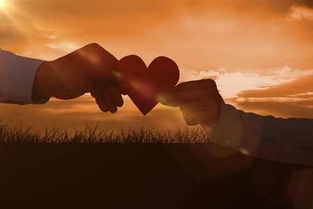 Couple holding paper heart shape paper against a couldy dayの写真素材