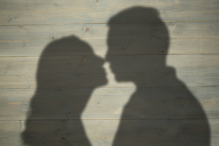 Profile view of couple about to kiss against bleached wooden planks backgroundの写真素材