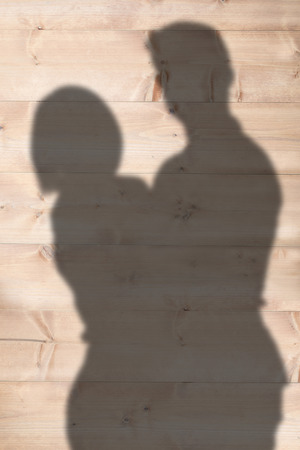 Portrait of happy couple standing against wooden planksの写真素材
