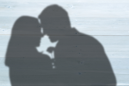 Happy couple holding flower against bleached wooden planks backgroundの写真素材