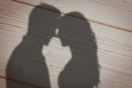 Happy young couple rubbing nose against brown wooden backgroundの写真素材