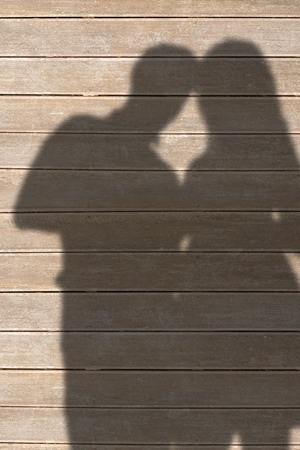Young couple holding hands against wooden planksの写真素材