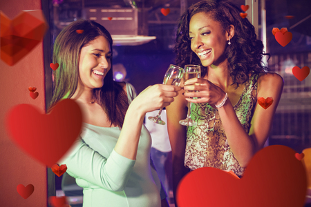 Happy women toasting champagne glasses against love heart patternの写真素材