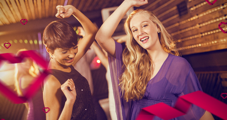 Two beautiful women dancing on dance floor against hearts