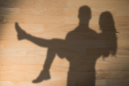 Portrait of boyfriend carrying girlfriend against bleached wooden planks backgroundの写真素材