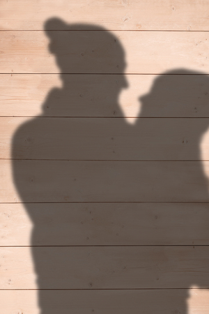 Smiling couple hugging and looking at each other against wooden planksの写真素材
