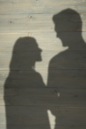 Attractive couple holding miniature house model against wooden planksの写真素材