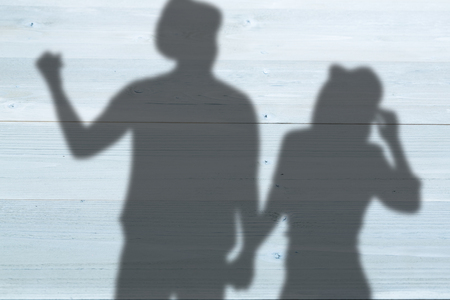 Cheerful man gesturing while holding woman hand against bleached wooden planks backgroundの写真素材