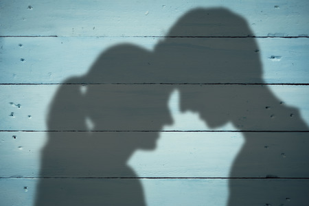 Couple looking at each other against painted blue wooden planksの写真素材