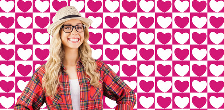 Gorgeous smiling blonde hipster with hands on hips against valentines day patternの写真素材
