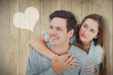 Couple embracing with arms around and looking away against wooden planksの写真素材