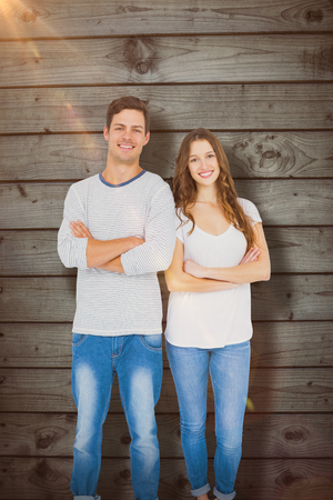 Portrait of happy couple with arm crossed against close-up of wooden fenceの写真素材