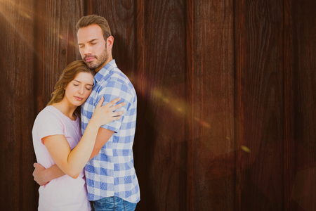 Happy young couple cuddling each other against woodの写真素材
