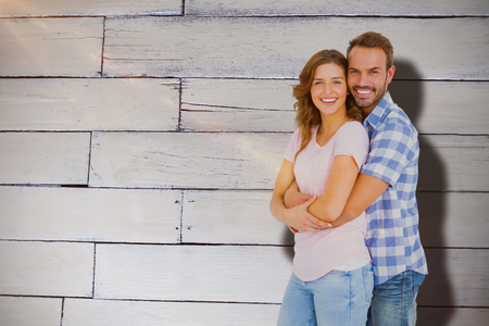 Happy young couple embracing against white wooden wallの写真素材