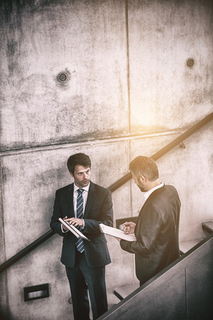 Businessmen discussing official reports on staircaseの写真素材