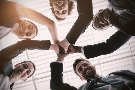 Low angle view of happy businesspeople giving high five in office premisesの写真素材