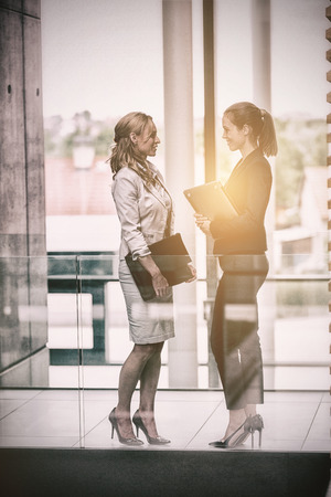 Businesswomen having conversation in officeの写真素材